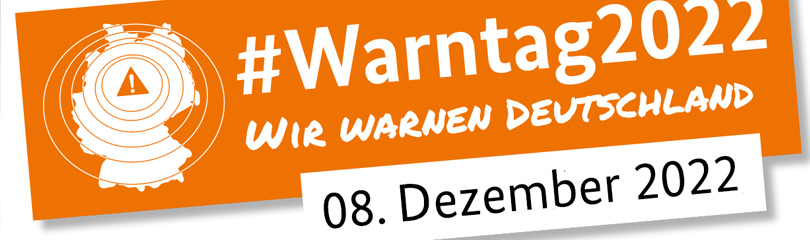 Weiße Deutschlandkarte mit Ausrufezeichen auf orangenem Hintergund, dazu die Aufschrift Warntag 2022, wir warnen Deutschland